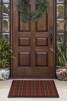 the front door is decorated with wreaths and potted plants