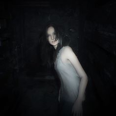 a woman standing in a dark room with her head turned to the side