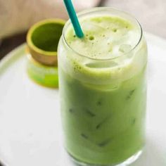 a green smoothie on a white plate with a blue straw in the cup next to it