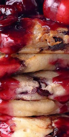 a stack of pancakes covered in jelly and cherries