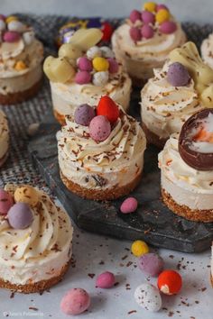 small cupcakes with white frosting and chocolate eggs on top, surrounded by candy candies