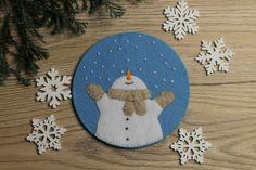 a snowman ornament on a wooden table surrounded by snowflakes