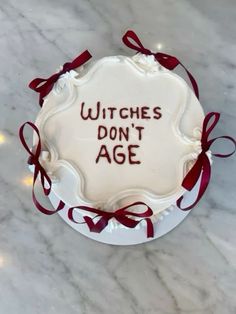 a cake with writing on it that says witches don't age and red ribbon around the edges