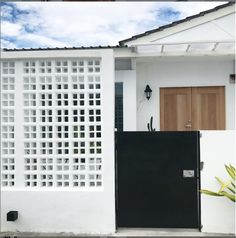 a white house with a black gate and wooden door