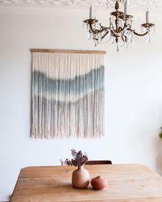 a chandelier hanging over a wooden table with two vases on it