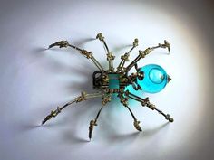 a metal spider sculpture sitting on top of a white table next to a blue ball