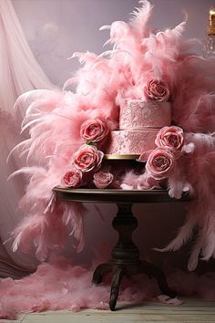 a cake with pink feathers and roses on a table