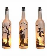 three bottles with halloween images on them and one has a light in the shape of a house