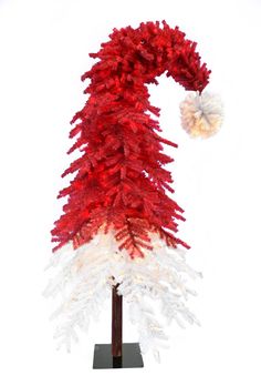 a red and white christmas tree on a stand with a pom - pom