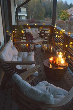 a deck with chairs and candles lit up on the top floor in front of an open window