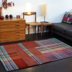 a living room area with a couch, chair and rug on the floor in front of a dresser