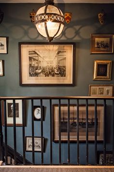 a stairway with pictures and framed photographs on the wall above it, along with a chandelier