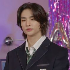 a young man in a suit and tie standing next to a purple wall with sequins on it