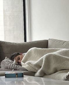 a woman laying on top of a couch under a blanket