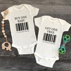 two baby onesuits with bar code on them next to a pacifier and beads