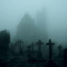 a cemetery with tombstones in the foreground on a foggy day