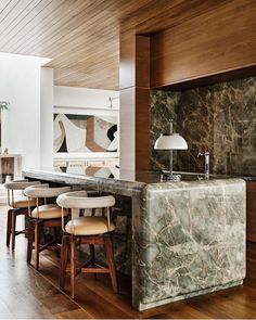 a kitchen with marble counter tops and stools next to an island in the middle