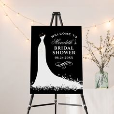 a welcome sign for a bridal shower on an easel next to a vase with flowers