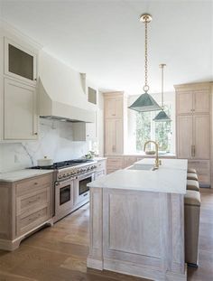 a large kitchen with an island in the middle and two pendant lights hanging from the ceiling