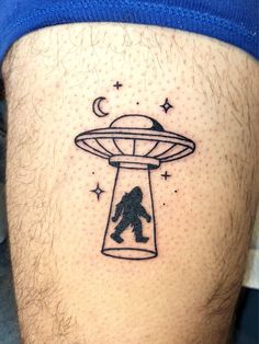 a man with a tattoo on his thigh that has an image of a bigfoot flying through the sky