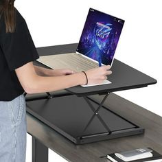 a woman using a laptop computer on top of a black table with a metal frame