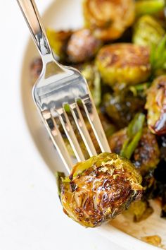 a fork with some food on it next to broccoli and other foods in a bowl