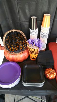 a table topped with plates and vases filled with pumpkins next to other items