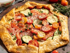 a pizza with tomatoes, cucumbers and parmesan cheese is on the table