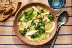 a bowl of chicken and vegetable soup next to some bread