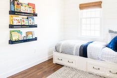 a bedroom with white walls and wooden flooring, two bookshelves on the wall