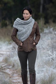 a woman standing in the middle of a field with her hands on her hips and wearing boots