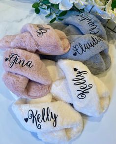 four personalized slippers are sitting on a white table with flowers in the background