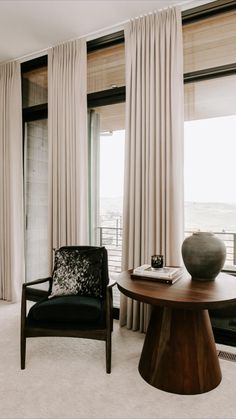 a living room filled with furniture next to a window covered in white curtains and drapes