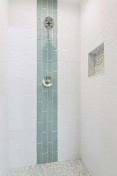 a shower head in a white bathroom with grey and white tiles on the wall behind it