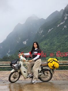 a woman sitting on a motor scooter with mountains in the backgroud