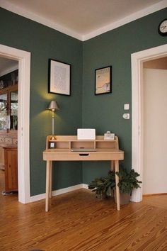 a room with green walls and wooden flooring has a white clock on the wall