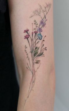 a flower tattoo on the right arm and leg, with purple flowers growing out of it