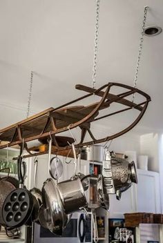 a rack with pots and pans hanging from it's ceiling in a kitchen