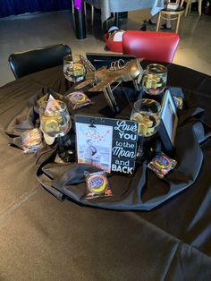 a table topped with jars filled with candy and candies on top of a black cloth covered table