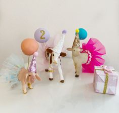 three figurines are standing next to each other with balloons and gifts in front of them