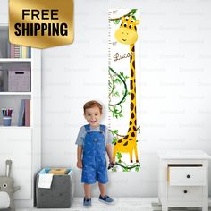 a little boy standing in front of a giraffe growth chart wall decal