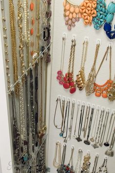 a closet filled with lots of different types of necklaces and bracelets hanging on the wall