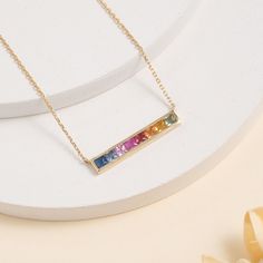 Embrace the vibrant beauty of the rainbow with this captivating Natural Long Rainbow Sapphire Bar Necklace. This stunning piece features a sleek bar pendant, crafted from solid 14k gold (available in yellow, white, or rose gold), meticulously set with a mesmerizing array of natural sapphires. Each sapphire gleams in a different captivating hue, from fiery reds and sunshine yellows to calming blues and deep purples. The rich tones of the gemstones are perfectly juxtaposed against the cool sheen of the gold, creating a truly eye-catching necklace. - Handmade - Solid Gold - Natural Sapphire - Total Sapphire Carat Weight: 0.60 ctw - Pendant Size: 4 x 15 mm 🛠 Your Sarah Elise piece is handcrafted with care! Ready-to-ship items go out within 3 business days. Made-to-order pieces typically take Cheap Personalized Rainbow Necklaces, Rainbow Bar Necklace, Sapphire Gold Necklace, Dainty Necklaces, Solid Gold Bracelet, Gemstone Choker, Rainbow Sapphires, Rainbow Necklace, Handmade Fine Jewelry