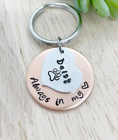 a metal keychain with a dog's paw and heart engraved on it