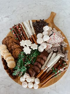 a wooden platter filled with lots of different types of cookies and pastries on top of a marble counter