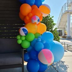 a bunch of balloons are hanging from a bench