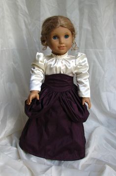 a doll with blonde hair wearing a purple dress and white shirt on a white background