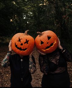 two people wearing pumpkin heads in the woods