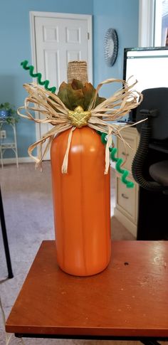 an orange pumpkin shaped vase sitting on top of a wooden table