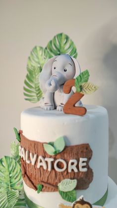 there is a cake that has an elephant on top of it and leaves around the edges